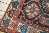 Distressed Bakhtiari rug with geometric serrated pattern and red dragon border.