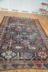 Distressed vintage hand-knotted Bakhtiari carpet, geometric pattern in indigo, red, green.
