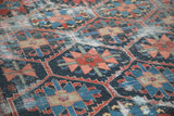Heavily distressed vintage Bakhtiari carpet featuring geometric flowers in indigo, red, green, and beige.