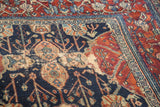 Distressed detail of vintage Bibikabad carpet with navy field, faded palmettes, and cherry red border.