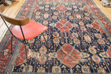 Distressed Bibikabad carpet with repeating navy, red, and peach medallion motifs.