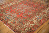 Distressed antique Malayer rug corner highlighting cranberry rose field, ivory Herati border, and soft blue tones.