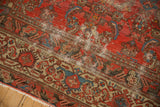 Angled view of antique Malayer rug border with distressed cranberry texture and intricate beige patterns.