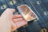 Detail of hand holding irregular antique beveled glass mirror with copper wire.
