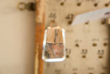 Copper wire on the bell-shaped antique mirror, with a reflection of patterned textile.