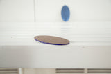 Oval Art Deco blue mirror's brown underside and prominent blue edge.