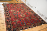 Distressed antique Sarouk rug with soft pile, bold red, and sprawling blue floral motifs.