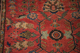 Sprawling floral motif in contrasting blues, blacks, and tan on the distressed red Sarouk rug.