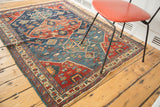Geometric border in indigo blue and cherry red, with distressed texture and fringe.