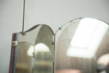 Antique tri-folding mirror hinge detail, showing top edge with aged glass and dark wood patina.