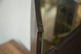 Patinaed dark wooden edge of the antique tri folding mirror's frame and metal hinges.