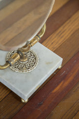 Corner of vintage white marble mirror base with a brass foot and subtle discoloration.