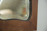 Beveled glass edge of the Art Deco mirror, showing aged surface and wooden frame patina.