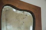 Art Deco mirror corner, showing beveled glass, aged silvering, and wood frame.
