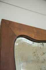 Art Deco mirror's wooden frame corner, rich patina, and unique aged glass surface.