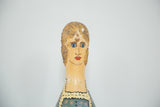 Vintage folk art painted bowling pin showing woman's face: blonde hair, blue eyes, red lips.
