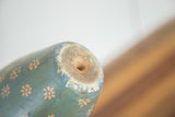Detail of worn folk art bowling pin base, revealing chipped teal paint and wood.