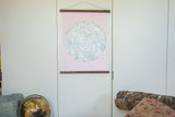 Pink moon chart revival wall hanging with walnut rods styled on a white door.