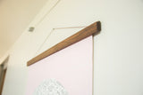 The rich grain of the handmade walnut wood rod holding the pink moon chart.