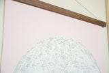 Intricate line art on the pink moon chart below its handmade walnut wood display rod.
