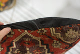 Antique Amu Darya rug pillow edge, red, aubergine geometric pattern, and black linen seam detail.
