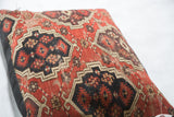 Amu Darya rug fragment pillow, geometric motifs in dark red, black, and neutral beige.