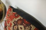 Antique Amu Darya rug fragment with geometric red, aubergine, beige pattern meeting black linen.