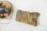 Textured antique Turkish rug fragment pillow showcasing muted blue and rose floral patterns.