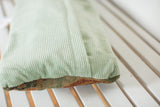 Ribbed light green velvet back of antique Turkish rug fragment pillow, showing patterned edge.