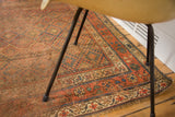 Artful distress with subdued bold geometric patterns on an antique Kurdish rug.
