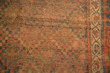 Distressed antique Kurdish rug showing aged pile and muted earthy tones with blue accents.
