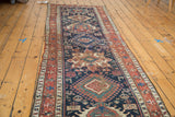 Distressed antique Karaja runner with geometric hooked diamonds and madder red borders.