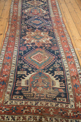 Distressed antique Karaja rug corner with textured wear, geometric motifs, and rich indigo field.