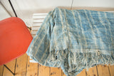 Handwoven indigo African textile throw, patterned blue and ivory with frayed tassels.
