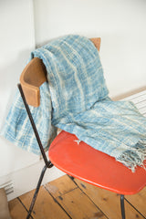 Hand-woven vintage African textile throw with blue and ivory patterns and tasseled fringe.