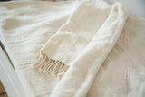 Folded ivory African textile throw, finely hand woven with subtle stripe design and short tassels.