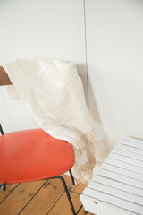 Close-up of finely hand-woven ivory African textile with natural short tassels.