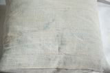 Textured close-up of the pillow's sun-faded powder blue indigo textile and horizontal stitch lines.