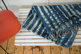 Hand-woven African textile featuring unique indigo and ivory resist-dyed pattern and short tassels.