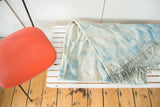 Hand woven African textile with mottled light blue indigo dye and soft ivory short tassels.