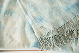 Close-up of hand woven African indigo textile in light blue and ivory with short tassels.