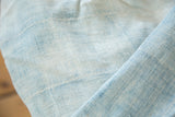 Close-up of hand-woven ivory and powder blue African indigo textile's textured surface.