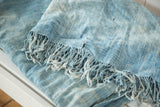Hand woven indigo textile detail, showing powder blue tones and short fringe.