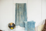Light blue indigo wall hanging's wooden dowel, hanging rope, and sun-faded textile.