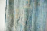 Close-up of vintage light blue indigo textile, showcasing its sun-faded tones and natural hand stitching.