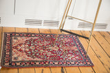 Antique Kerman mat with a tree of life motif and magenta field styled in a room.