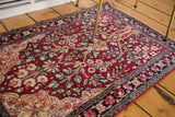 Angled view of an antique Kerman rug highlighting the magenta field and tree of life motif.