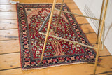 Antique Kerman rug mat with a magenta tree of life design in a lifestyle setting.
