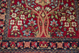 The navy floral border adjoining the base of the Tree of Life motif on an antique Kerman rug.
