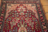 Angled view of the antique Kerman rug's tree of life motif on a rich magenta field.